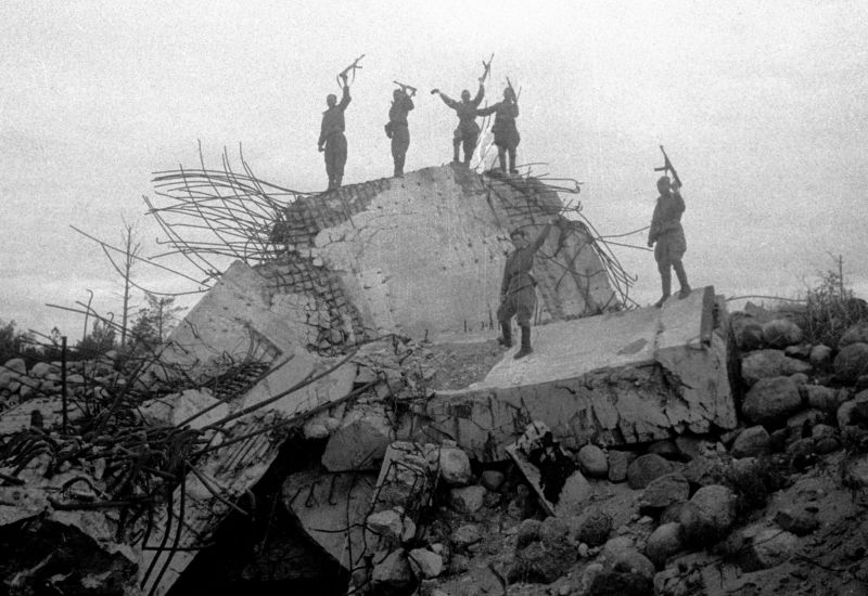 Бойцы Ленинградского фронта на взорванном вражеском ДОТе (1944 г.). Автор: Яков Рюмкин. Фото: waralbum.ru/386662/ Бойцы Ленинградского фронта на взорванном вражеском ДОТе (1944). Фото: waralbum.ru/386662/