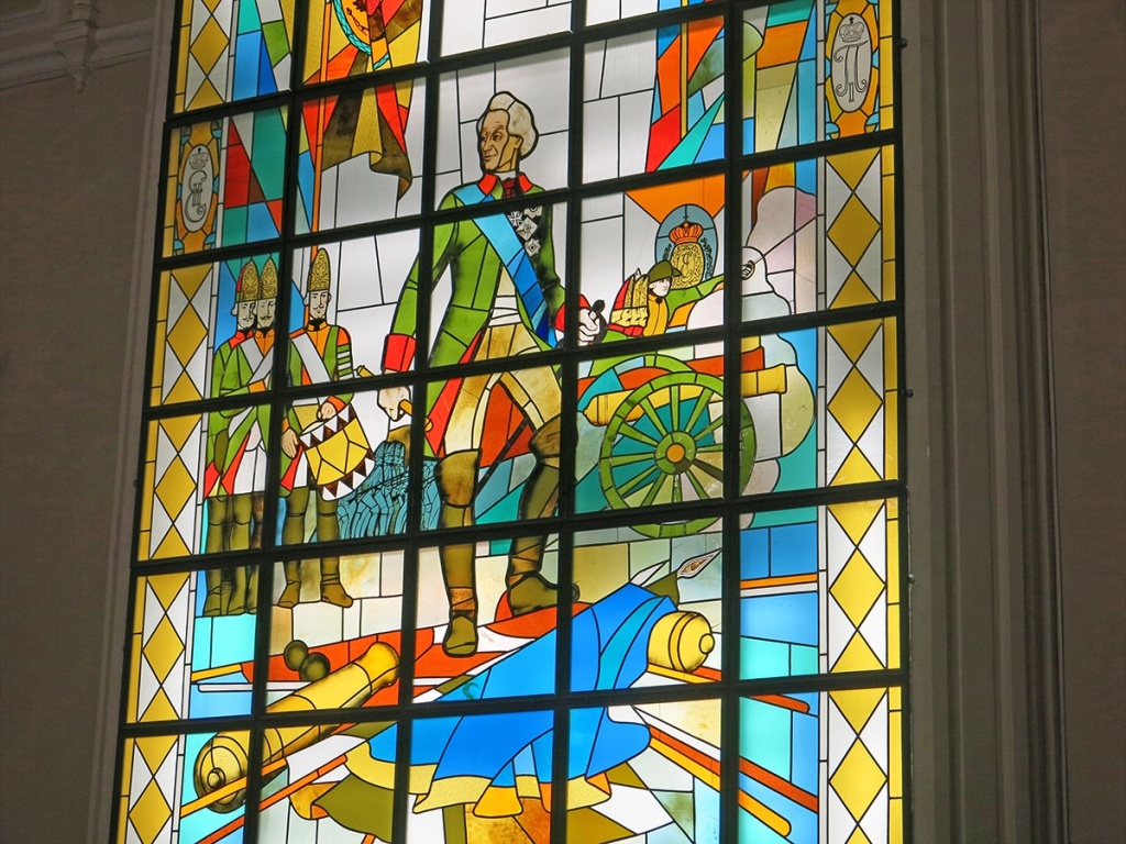 Витраж в Центральном зале музея, на котором в величественной позе в стиле парадных портретов XVIII века изображён Суворов.